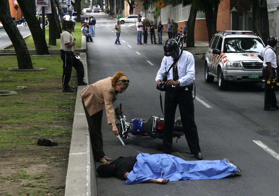 An assailant lies dead outside a bank after being killed by an armed victim of the robbery in the wealthy neighborhood of La Castellana in Caracas, November 18, 2008.