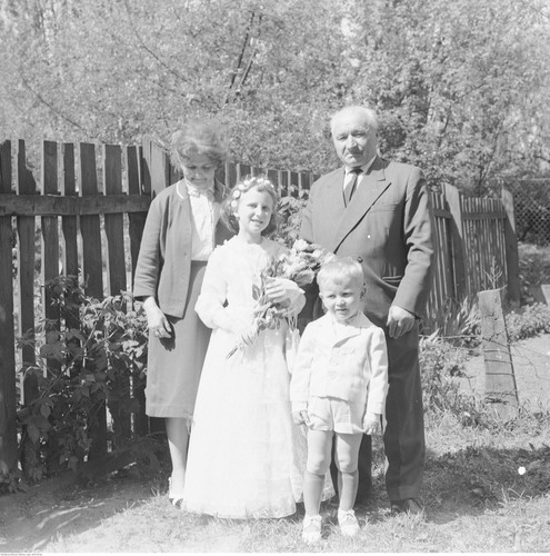 Dziewczynka w stroju komunijnym z dziadkami i bratem