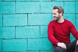 man-wearing-red-sweatshirt-and-black-pants-leaning-on-the-845434