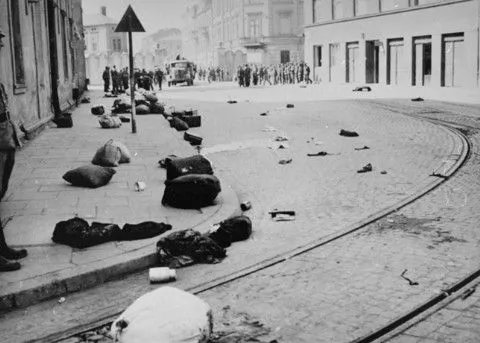 Mienie porzucone przez deportowanych, dzisiejsza ul. Lwowska (ówcześnie ul. Salinarna) w tle brama III getta, marzec 1943