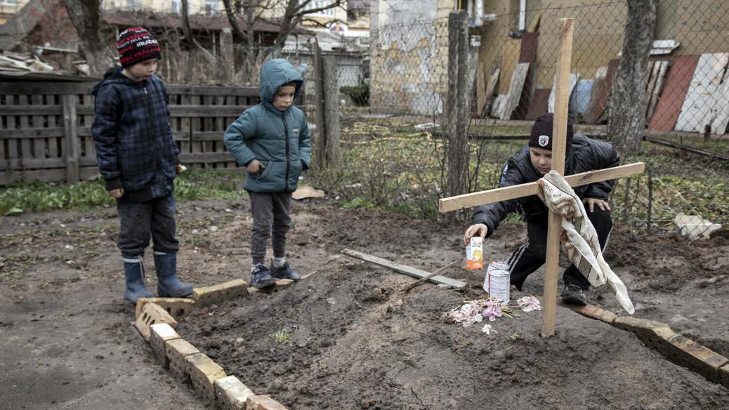 Wojna w Ukrainie. Dzieci na grobie matki zabitej w Buczy i pochowanej na podwórku domu