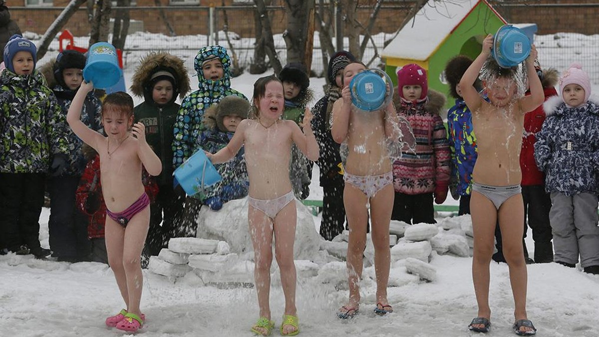 Children watch their classmates pour cold water on themselves, under the watch of fitness coach Oksa