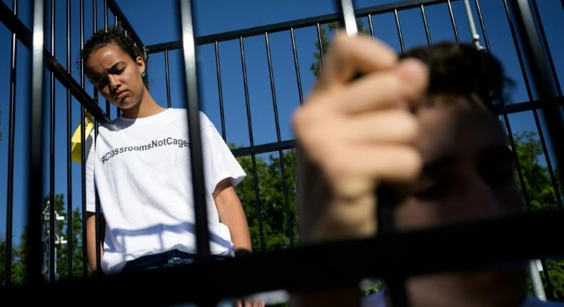 Three teens wearing t-shirts with #ClassroomsNotCages scrawled across the front stood inside a small cage erected outside the gates of the United Nations's European headquarters