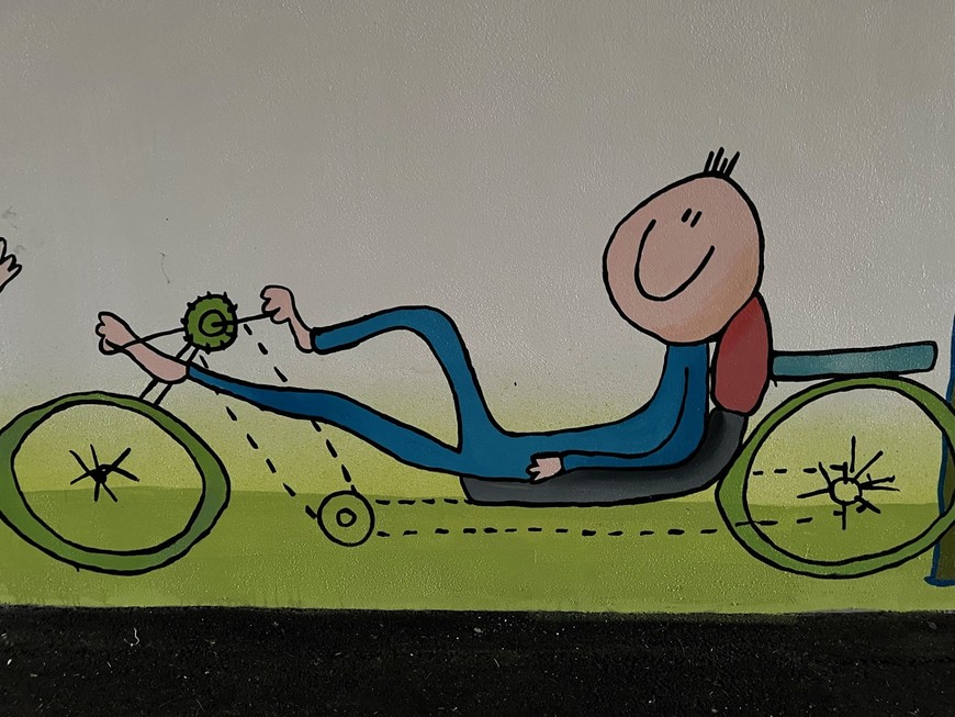 Na muralu możemy zobaczyć wielu postaci na rowerach