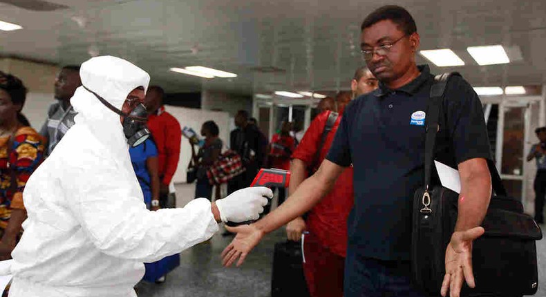 A health official uses a thermometer on a passenger at the international airport in Lagos, Nigeria