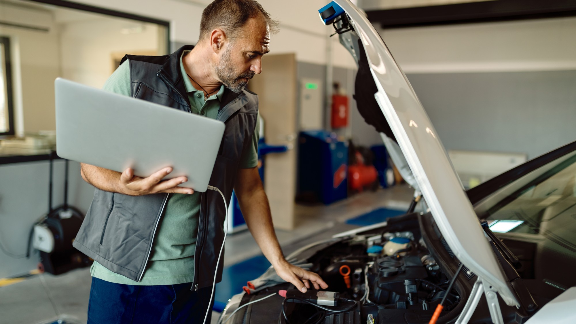 Automechanik v nezávislom servise používa modernú diagnostiku na opravu staršieho vozidla. 