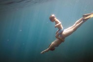 Underwater view of boy and mother diving