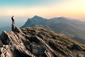 businessman hike on the peak of rocks mountain at sunset