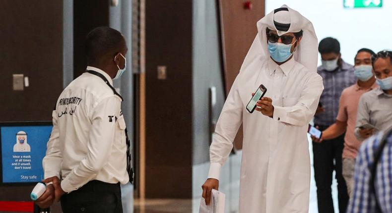 A mask-clad passenger shows his phone to a security guard at the Doha Metro, to show a green status (signifying an all-clear from coronavirus) on the Ehteraz smartphone app upon entering a station in Qatar's capital on September 1, 2020. Photo by KARIM JAAFAR/AFP via Getty Images)