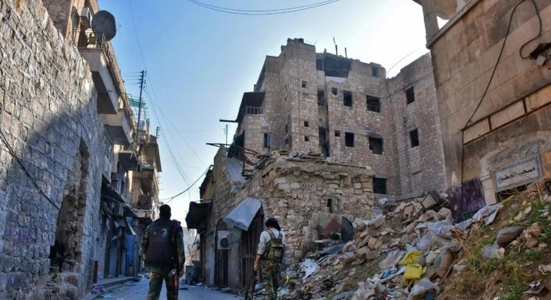 Syrian pro-government forces walk past rubble in old Aleppo's Jdeideh neighbourhood on December 9, 2016