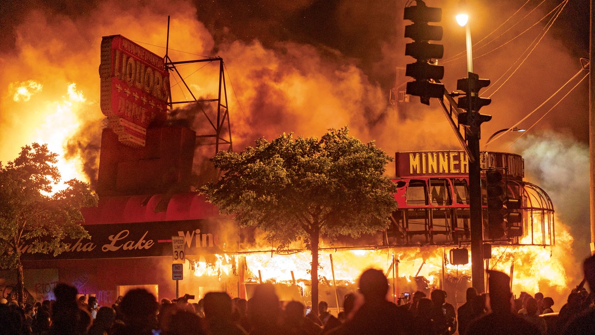 Protestujący po śmierci George'a Floyda gromadzą się pod płonącym sklepem z alkoholem w Minneapolis. Fot. Katem Yucel/AFP/East News