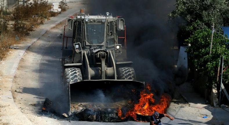 A Palestinian youth runs from the path of an Israeli army bulldozer during clashes in the village of Kobar, west of Ramallah, on July 22, 2017