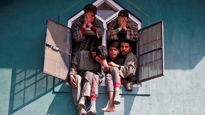 People react as they sit in a window of a mosque during the funeral of Tauseef Ahmad Wagay, a suspec