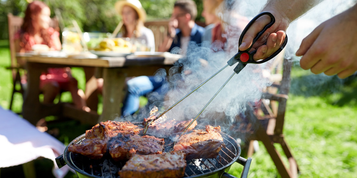 man cooking meat on barbecue grill at summer party