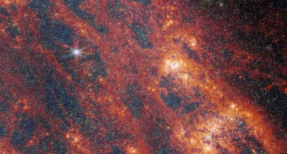 Na powiększonym zdjęciu z teleskopu Jamesa Webba widać ciemnoczerwone obszary kosmicznego pyłu, który przenika galaktykę M51. Czerwone regiony pokazują światło złożone z cząsteczek tworzących się na ziarnach pyłu