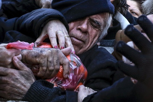 A man grasps a bag of tangerines as people receive free produce, handed out by farmers, during a pro