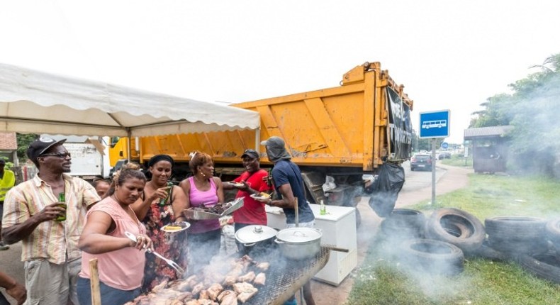 People eat at a barbecue at a road block in Cayenne, French Guiana, during a string of region-wide protests and road blockades