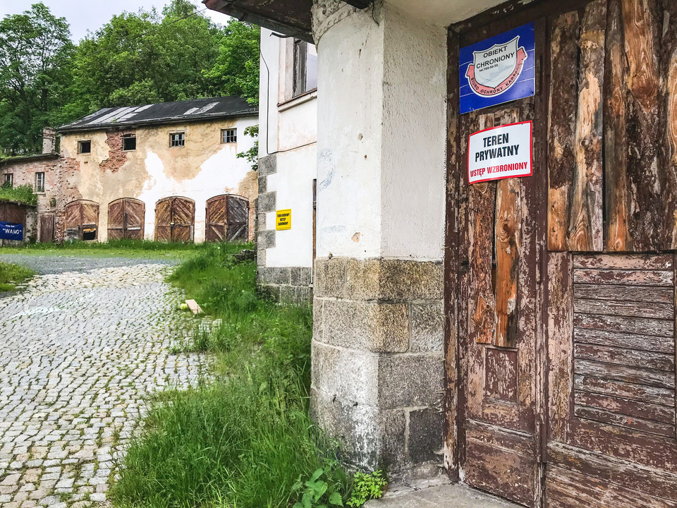 Wejście do budynku, w tle zbudowania gospodarcze