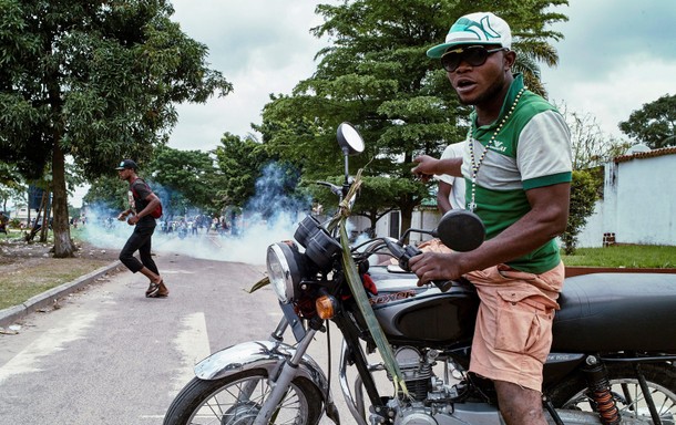 A moto-taxi driver reacts as riot police fire teargas towards anti-government protesters gathered to