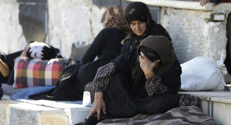 Displaced Syrians who fled areas controlled by the Islamic State with their families gather at Aleppo's Ramussa bus station on July 4, 2017