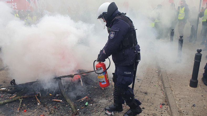Policjant gasi ogień przed Sejmem