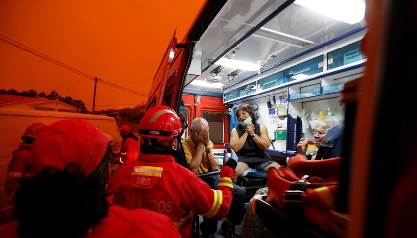 Local residents react as they are evacuated, during a forest fire, from the village of Derreada Cime