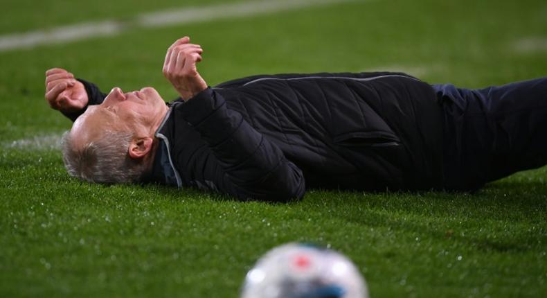 Freiburg head coach Christian Streich lies on the pitch after being barged by Frankfurt captain David Abraham on Sunday.