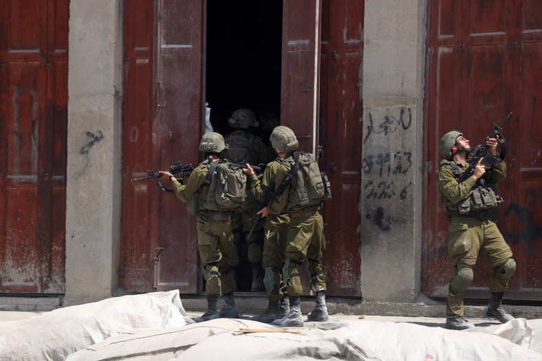 Członkowie izraelskich sił bezpieczeństwa zajmują pozycje na miejscu strzelaniny na południe od miasta Hebron na Zachodnim Brzegu, 21 sierpnia 2023 r.