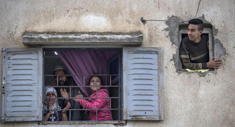 Moroccans confined at home thank the authorities from their windows as security forces and health workers instruct people to return to and remain at home as a measure against the COVID-19 coronavirus pandemic, in Rabat's district of Takadoum