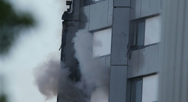 An arm holding a cloth can be seen waving from a window of Grenfell Tower as smoke rises from a lower window