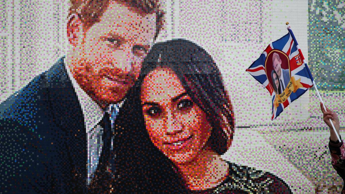 A girl waves a flag next to a LEGO brick mosaic of Britain's Prince Harry and Meghan Markle in Windsor