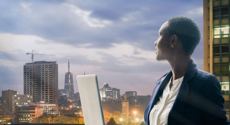 Businesswoman holding her laptop by the Nairobi city skyline