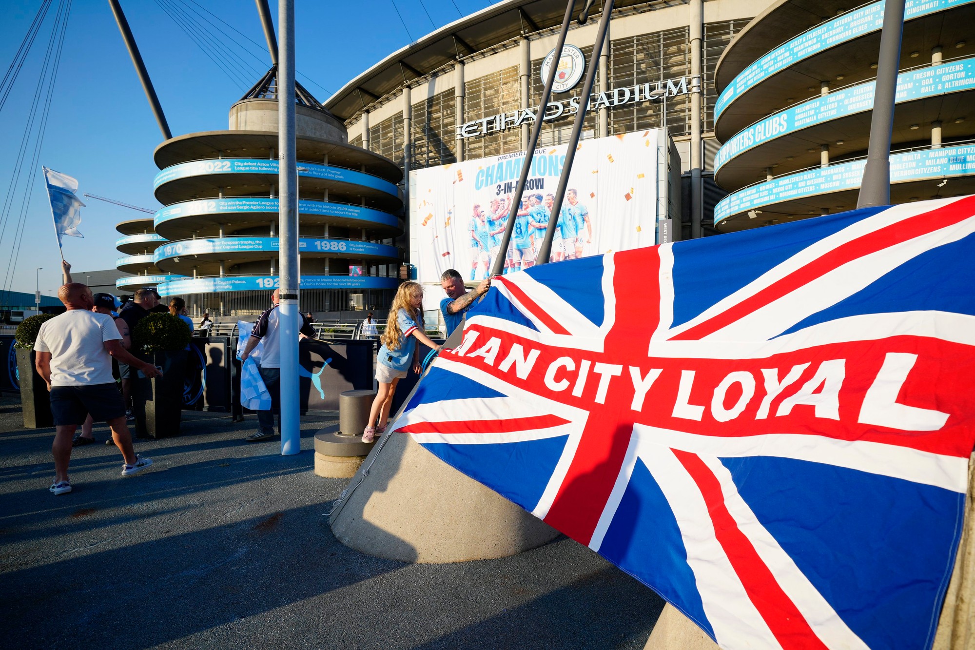 Fanúšikovia Manchestru City oslavujú obhajovu titulu pred Etihad Stadium.