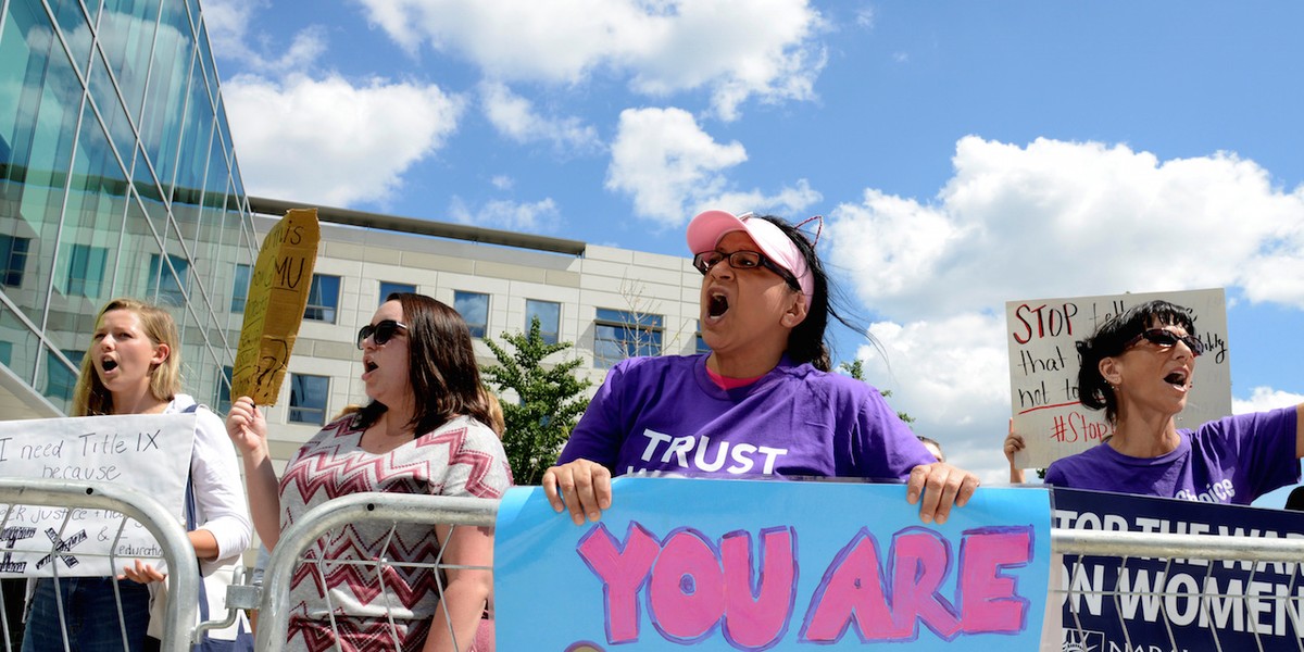 People demonstrate outside the hall where Education Secretary Betsy DeVos delivered a major policy address on Title IX enforcement.