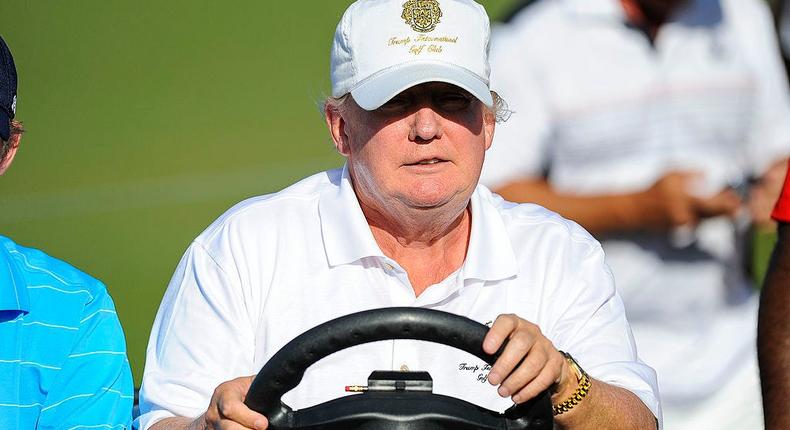 Former US President Donald Trump drives a buggy at one of his golf clubs.