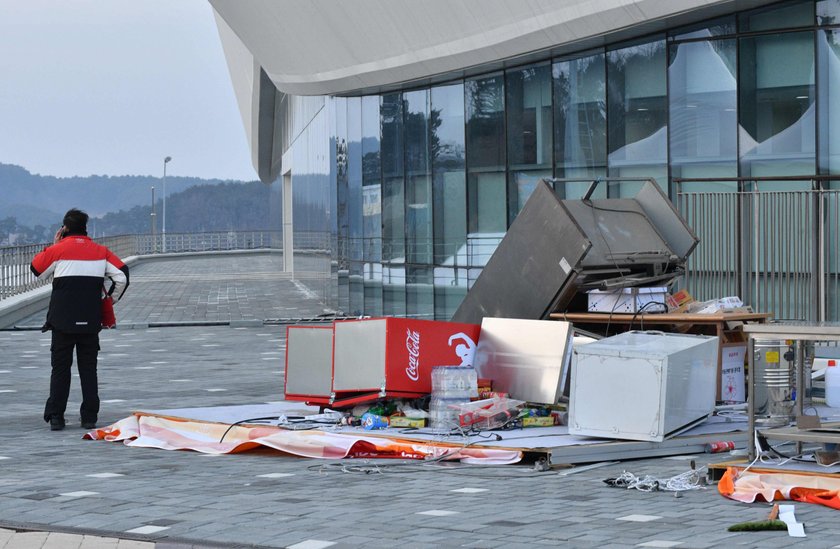 Firefighters assess the damage to a food stall that was blown over by the wind