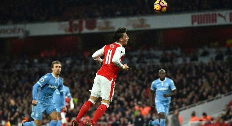 Arsenal's German midfielder Mesut Ozil (C) heads the ball to score their second goal against Stoke City at the Emirates Stadium in London on December 10, 2016