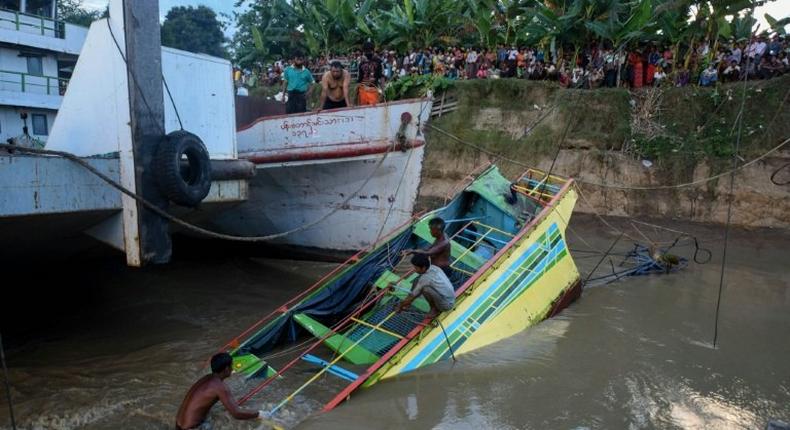 Rescue workers stand on the partly sunken ferry that capsized on the Chindwin River killing nearly 50 people four days ago