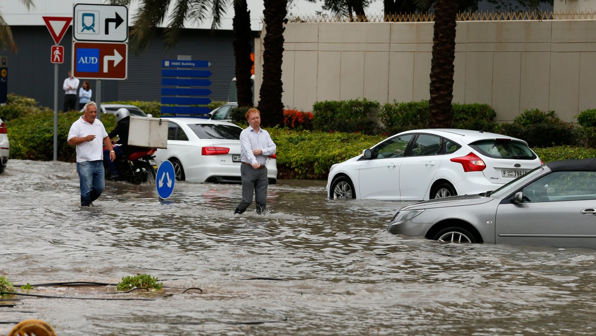 People walk through a flooded street during a rain storm in Dubai