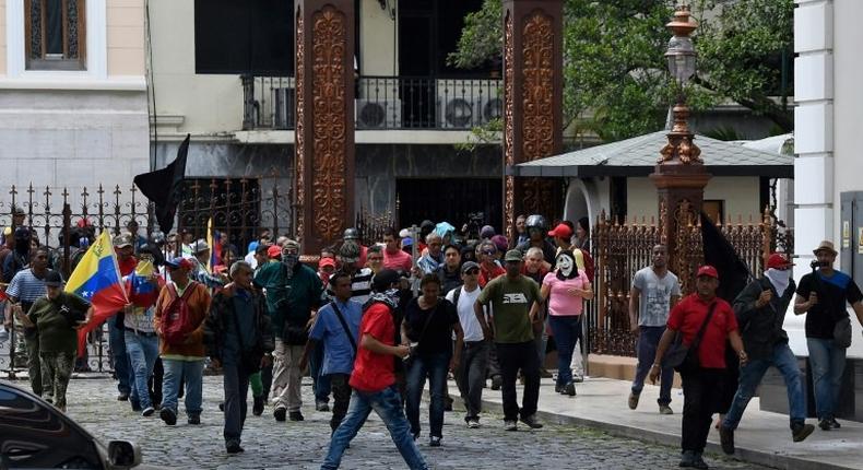 Stick-wielding supporters of Venezuelan President Nicolas Maduro broke through the front gate of the National Assembly building and set off fireworks in the interior gardens