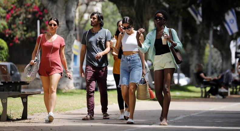 People walk without masks on a Tel Aviv boulevard on April 18, 2021, the day Israel rescinded its outdoor mask mandate.
