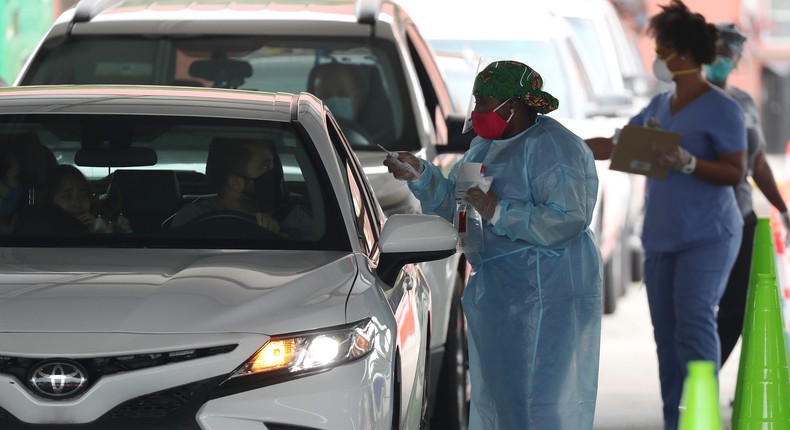 A health care worker directs a person to use a nasal swab for a self administered test at the new federally funded COVID-19 testing site at the Miami-Dade County Auditorium on July 23, 2020 in Miami, Florida