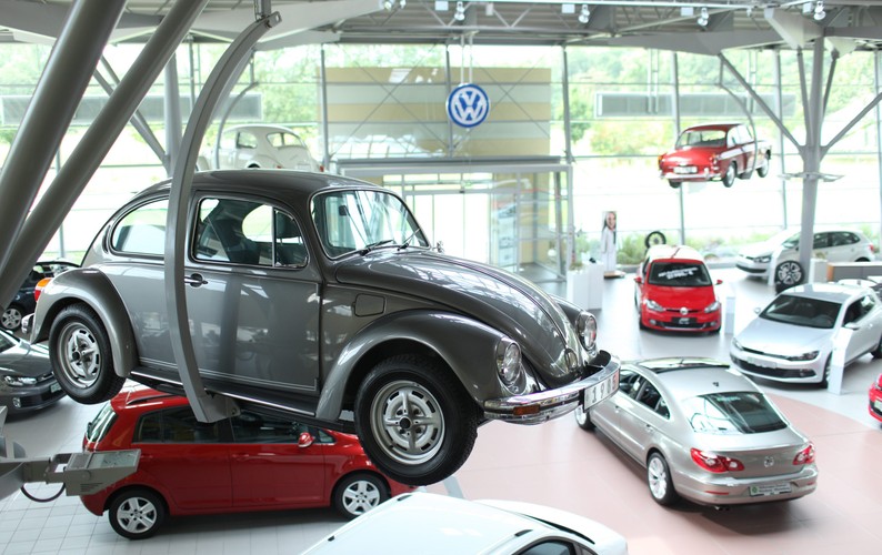 Volkswagen Beetle. Ten model ze stajni niemieckiego giganta motoryzacji pozostaje jednym z najbardziej rozpoznawanych symboli XX wieku. „Garbus” był z nami i podczas II wojny światowej, i podczas legendarnego festiwalu Woodstock, ale również podczas upadku Muru Berlińskiego. Garbus jest także bohaterem wielu filmów i tekstów popkultury. Auto to było popularne szczególnie w gronie młodych kobiet, jednakże ostatnie zmiany designu miały zachęcić do tego modelu także klientów płci męskiej. Na zdjęciu: Salon Volkswagena w Norymberdze. Klasyczny model Volkswagena Beetle zawieszony na pierwszym planie. Norymberga, Niemcy, 22.07.2009.