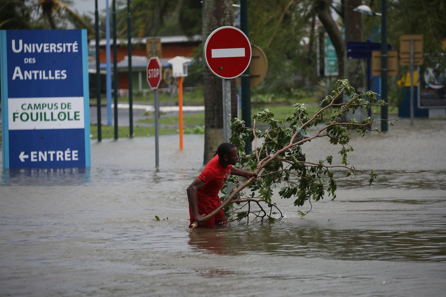 A man removing a branch in a flooded street in Pointe-a-Pitre, on the island of Guadeloupe, after Maria passed through.
