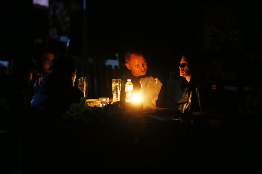 Ludzie siedzący przy świecach podczas zaplanowanych przerw w dostawie prądu w Odessie 25 października 2022 r.