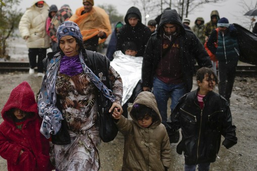 Migrants walk under rain after crossing the border from Greece into Macedonia, near Gevgelija