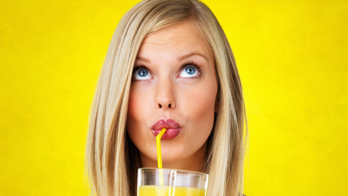 Thoughtful woman sipping orange juice