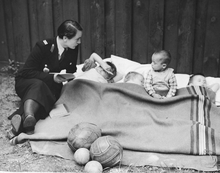 Policjantka czyta dzieciom przebywającym w Izbie Dziecka. 1937 rok. Fot. Narodowe Archiwum Cyfrowe.