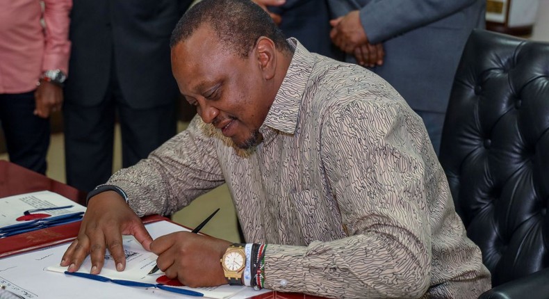 President Uhuru Kenyatta signing a document in his office