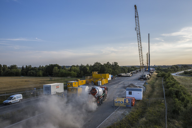 Pracownicy stoją obok betonomieszarki podczas trwających prac naprawczych na autostradzie A20 niedaleko Tribsees, Niemcy, w środę, 1 sierpnia 2018 roku. Fotograf: Rolf Schulten / Bloomberg